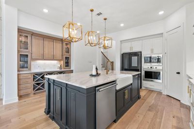 Kitchen with a center island, white cabinetry, light hardwood / wood-style flooring, appliances with stainless steel finishes, and tasteful backsplash | Image 3