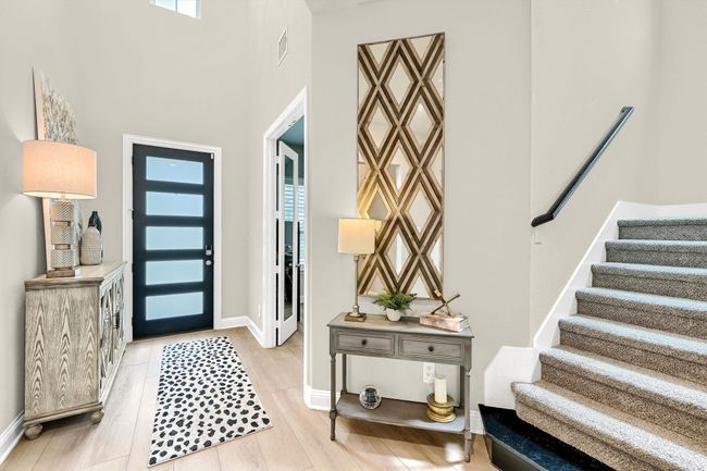 Entryway featuring visible vents, stairway, light wood finished floors, a high ceiling, and baseboards | Image 8