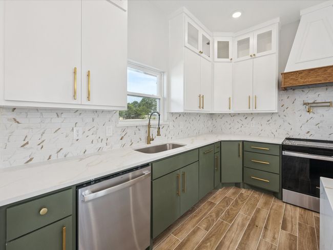 Kitchen with stainless steel appliances, green cabinetry, custom range hood, white cabinetry, and recessed lighting | Image 13