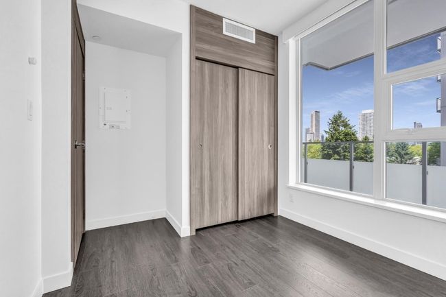Unfurnished bedroom with dark wood finished floors, a closet, and multiple windows | Image 12