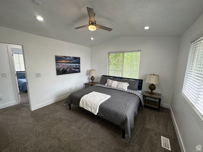 Bedroom featuring carpet flooring, multiple windows, baseboards, lofted ceiling, and ceiling fan | Image 8
