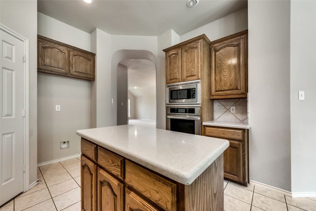 Kitchen with stainless steel appliances, arched walkways, light tile patterned floors, a center island, and recessed lighting | Image 14