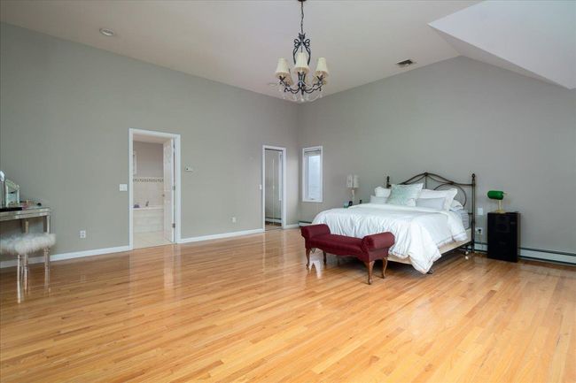 Bedroom with a chandelier, wood finished floors, a baseboard radiator, and lofted ceiling | Image 21