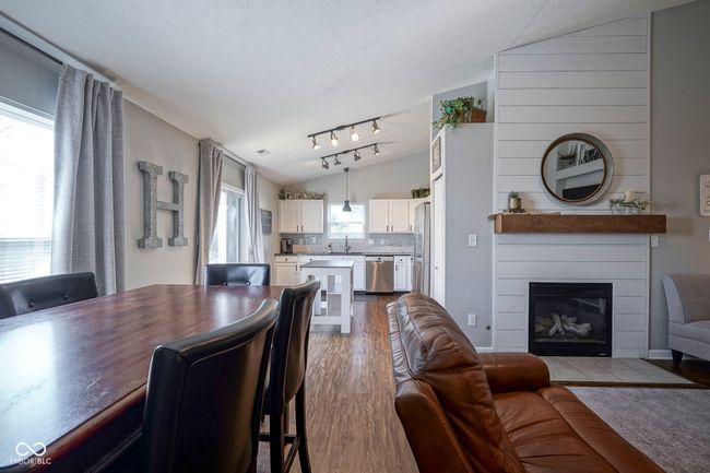 dining space featuring dark wood finished floors, a large fireplace, and lofted ceiling | Image 11