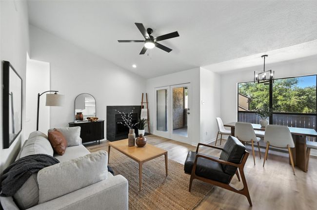 Living room featuring light wood-type flooring, vaulted ceiling, a chandelier, a ceiling fan, and french doors | Image 10