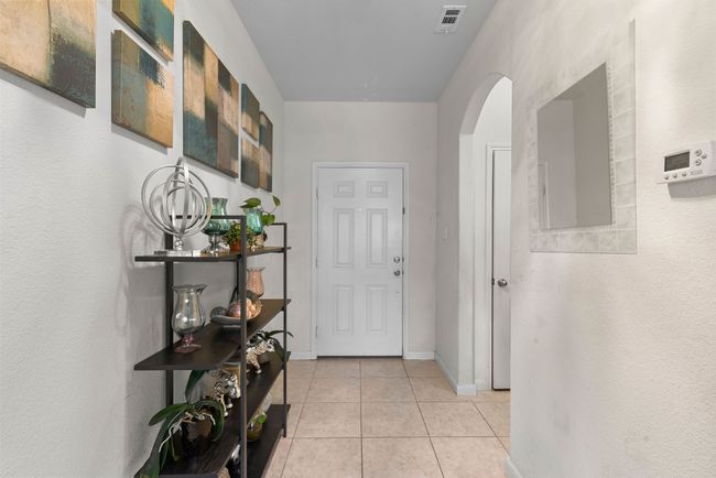 Hallway with baseboards, arched walkways, visible vents, and light tile patterned floors | Image 18