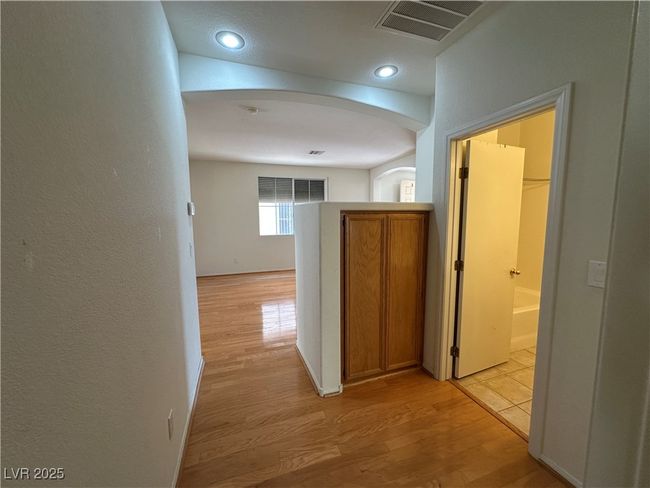 Hallway featuring light wood-style floors, arched walkways, a textured wall, and recessed lighting | Image 21