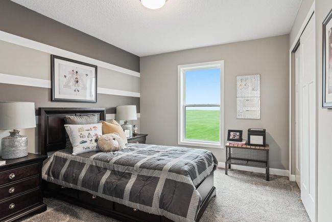 (Photo of a decorated model, actual homes finishes will vary) One of three generously sized upper level secondary bedrooms with spacious closets. | Image 14