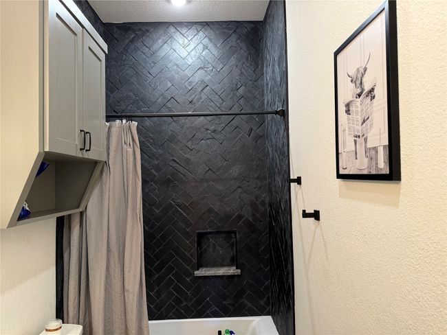 Full bathroom featuring shower / bathtub combination with curtain and a textured wall | Image 32