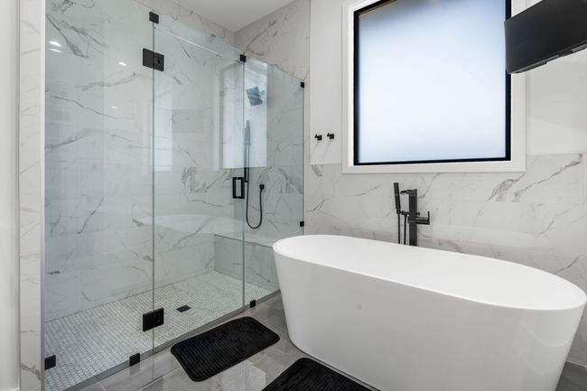 Bathroom with a freestanding bath, a marble finish shower, tile walls, and marble finish floors | Image 16