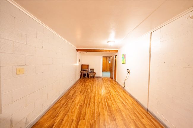 Corridor with light wood-style flooring, concrete block wall, and ornamental molding | Image 35