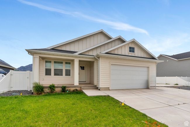 View of front facade featuring board and batten siding, driveway, an attached garage, a porch, and a gate | Image 24
