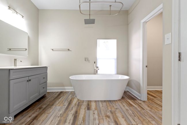 bathroom with vanity, a soaking tub, wood finished floors, and baseboards | Image 21