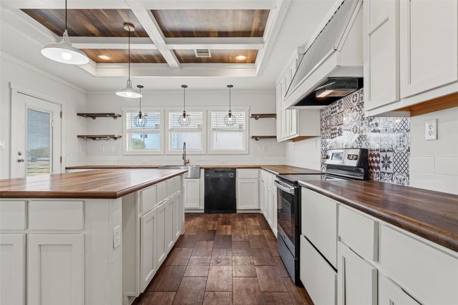 Kitchen featuring open shelves, butcher block countertops, stainless steel range oven, coffered ceiling, and a wood ceiling with exposed beams | Image 8