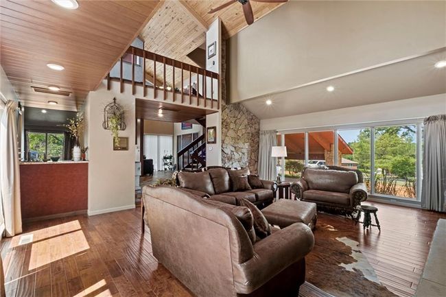 Living area featuring healthy amount of natural light, hardwood / wood-style floors, stairway, high vaulted ceiling, and a ceiling fan | Image 5