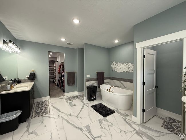 Bathroom with vanity, a walk in closet, a freestanding tub, recessed lighting, and visible vents | Image 35