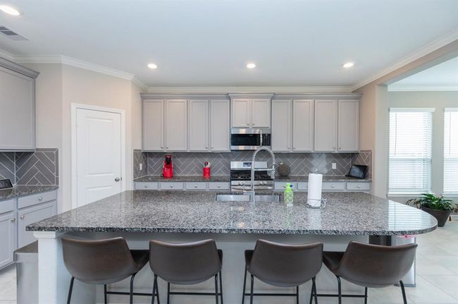 large granite island, bar seating, and sleek gray cabinetry | Image 13