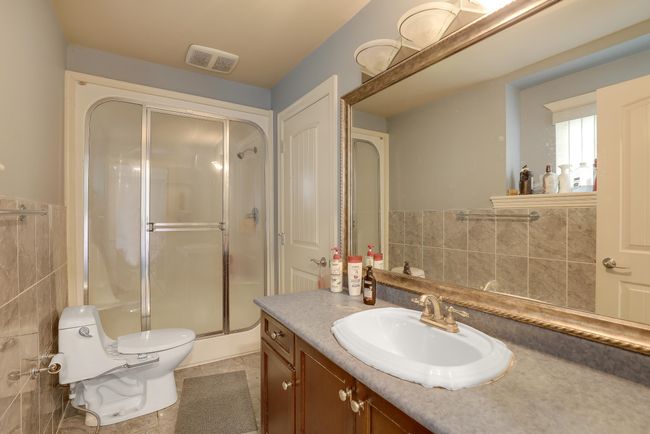 Full bathroom featuring a shower stall, visible vents, toilet, tile walls, and vanity | Image 23