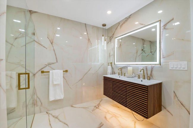 Full bathroom featuring double vanity, tile walls, a marble finish shower, and marble tiled flooring | Image 13