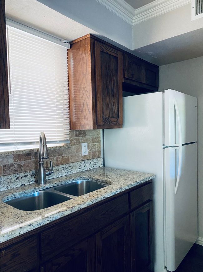 Kitchen featuring crown molding, backsplash, freestanding refrigerator, and light stone countertops | Image 7