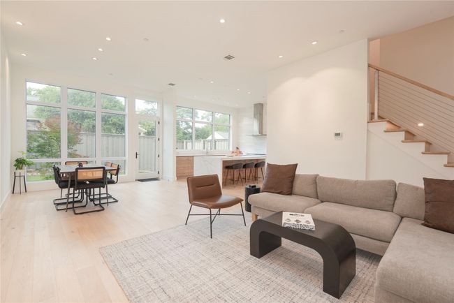 Main living area with hardwoods is open to kitchen and dining and views front courtyard and backyard. | Image 5