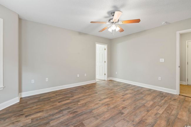 Empty room with a ceiling fan, wood finished floors, baseboards, and a smoke detector | Image 20