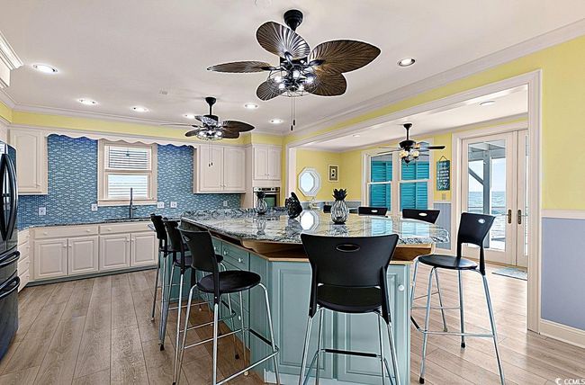 Kitchen with white cabinetry, stainless steel oven, a breakfast bar, and a sink | Image 13