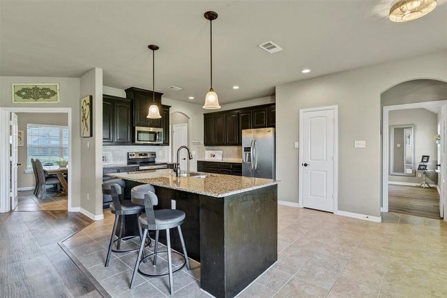 Kitchen featuring backsplash, a kitchen island with sink, light wood-type flooring, appliances with stainless steel finishes, and sink | Image 11