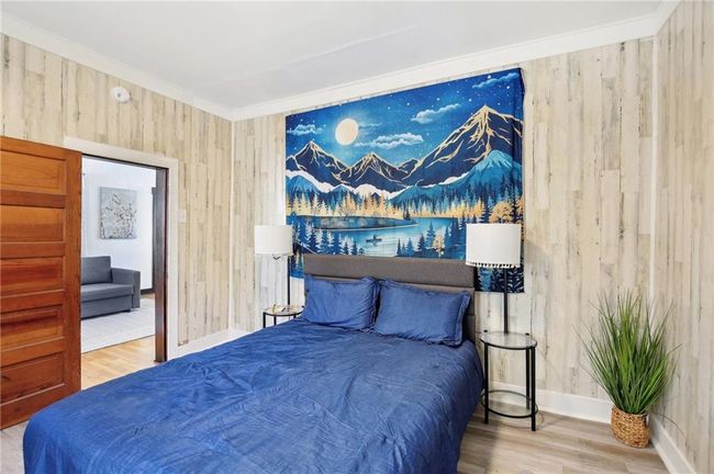 Bedroom with baseboards, wooden walls, wood finished floors, and crown molding | Image 13