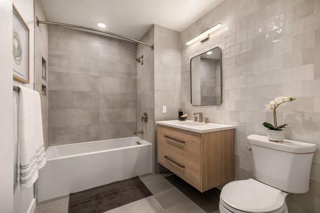 Full bathroom with toilet, tile walls, vanity, tub / shower combination, and tile patterned flooring | Image 10