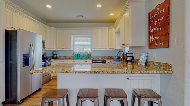 Spacious kitchen featuring stainless steel appliances, all the essential kitchenware, granite countertops, and additional breakfast bar seating for extra convenience. | Image 16