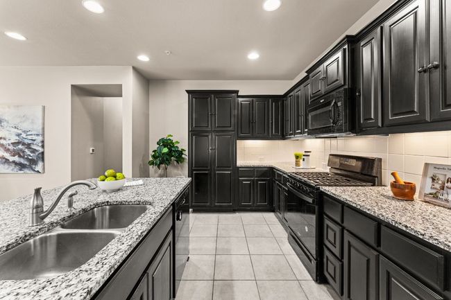 Kitchen with black appliances, dark cabinets, recessed lighting, backsplash, and light tile patterned floors | Image 8