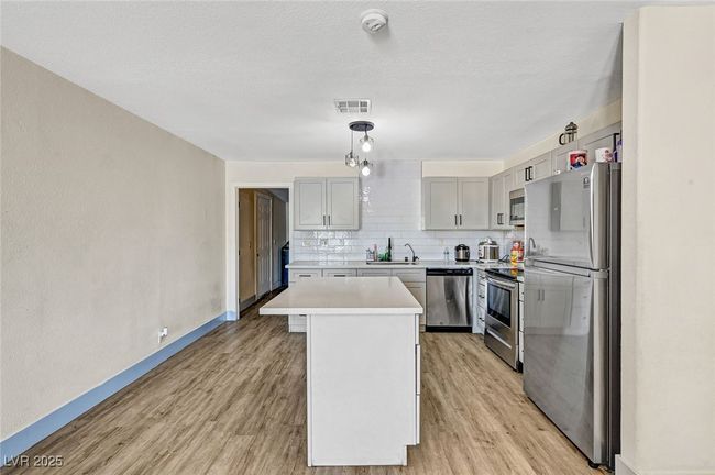 Kitchen with appliances with stainless steel finishes, light wood-style floors, light countertops, and backsplash | Image 17
