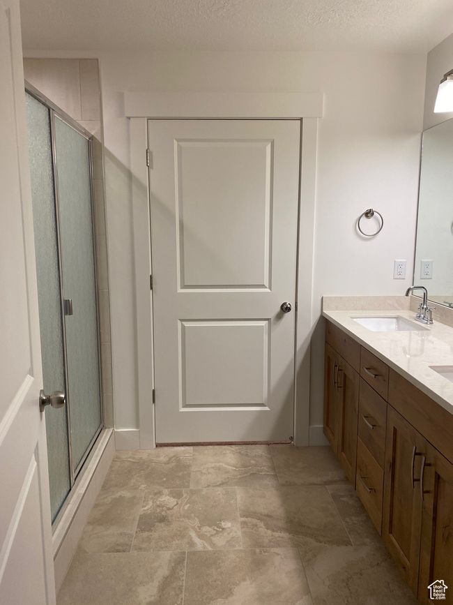 Full bathroom with a textured ceiling, a sink, double vanity, and a stall shower | Image 11