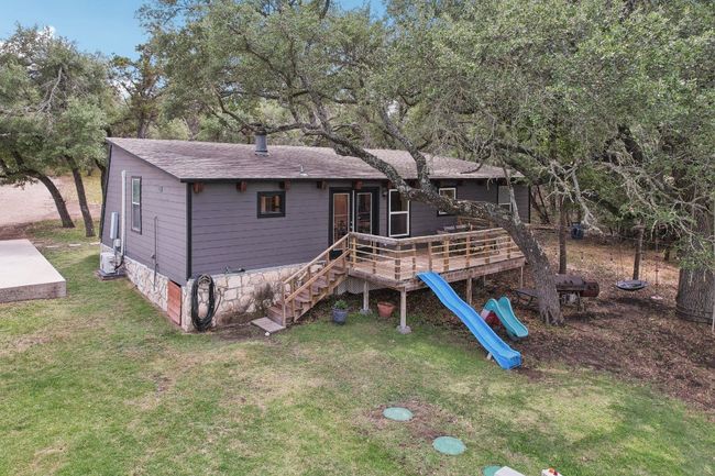 Back of property with a yard, a deck, a shingled roof, and stairway | Image 28