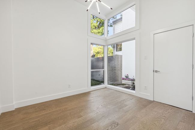 Empty room featuring baseboards, plenty of natural light, wood finished floors, and a towering ceiling | Image 25