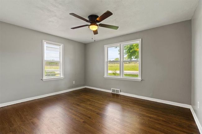 Spare room featuring healthy amount of natural light, wood finished floors, and a ceiling fan | Image 14