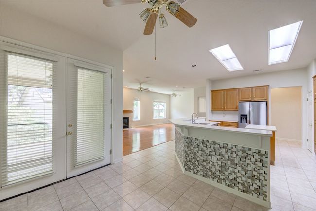 Kitchen with stainless steel fridge with ice dispenser, a ceiling fan, light tile patterned floors, and open floor plan | Image 11