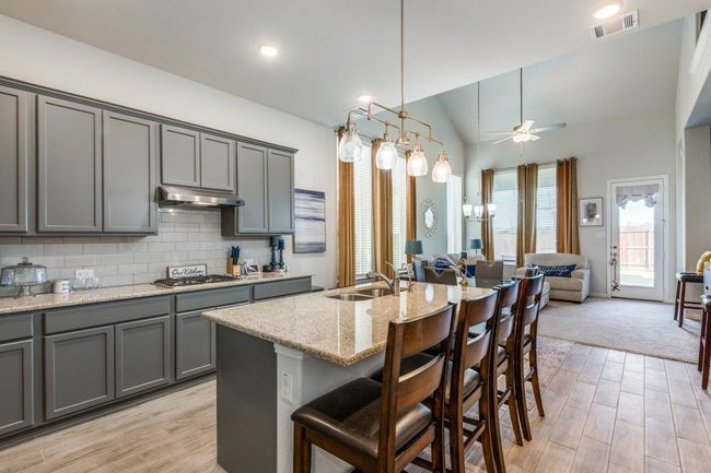 Kitchen featuring gray cabinetry, a sink, ceiling fan, under cabinet range hood, and stainless steel gas stovetop | Image 5