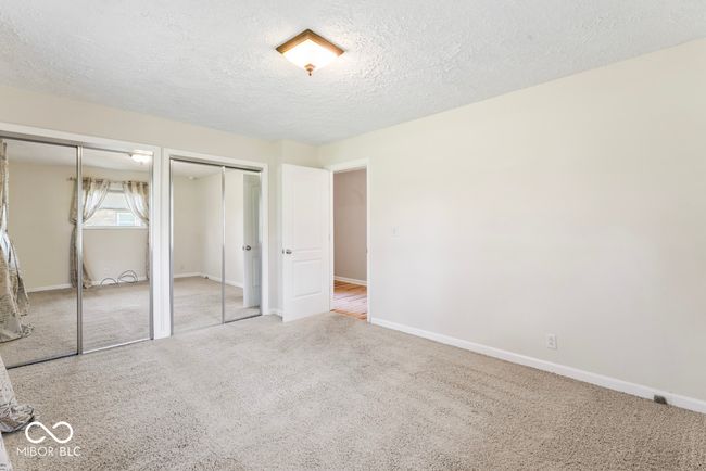 unfurnished bedroom featuring two closets, baseboards, carpet, and a textured ceiling | Image 20