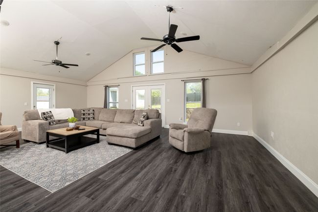 Living area featuring wood finished floors, ceiling fan, baseboards, and high vaulted ceiling | Image 20