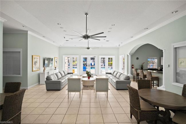 Living area with a ceiling fan, light tile patterned flooring, arched walkways, and a wealth of natural light | Image 36