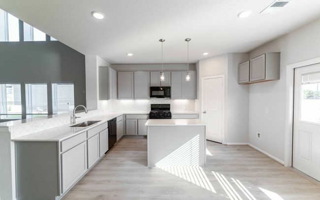 Kitchen with gray cabinets, black appliances, tasteful backsplash, light countertops, and recessed lighting | Image 7