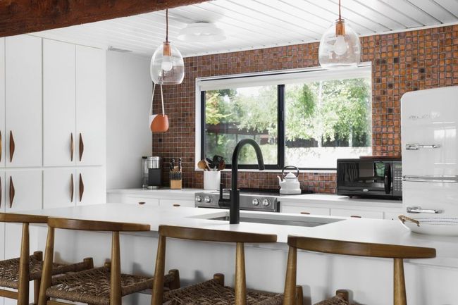 Kitchen with hanging light fixtures, light countertops, black microwave, and freestanding refrigerator | Image 7