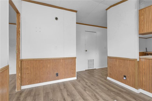 Spare room with wainscoting, wood finished floors, ornamental molding, and wood walls | Image 11