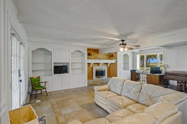Living area with a fireplace, crown molding, and built in features | Image 22