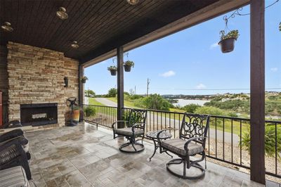 View of terrace with an outdoor stone fireplace and a balcony | Image 1