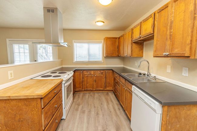 Kitchen featuring island exhaust hood, light wood-type flooring, white appliances, and sink | Image 8