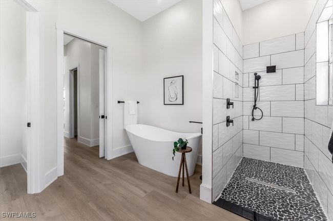 Bathroom with a tile shower, a freestanding tub, and wood finished floors | Image 15