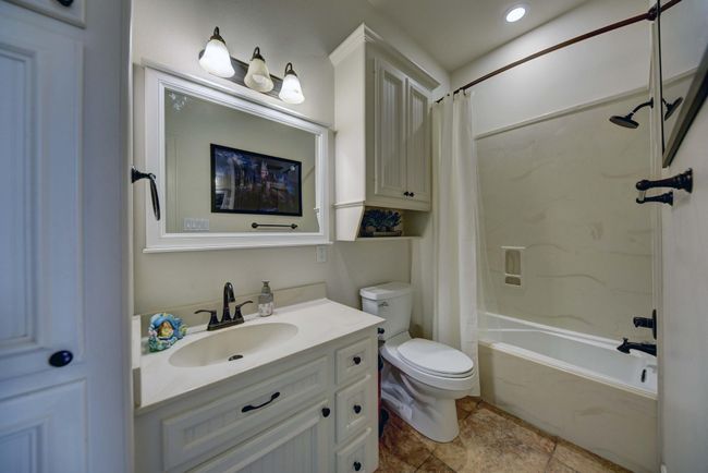 Elegant Guest Bathroom featuring vanity, ample storage, and a modern shower-tub combo, ideal for visitors. | Image 21